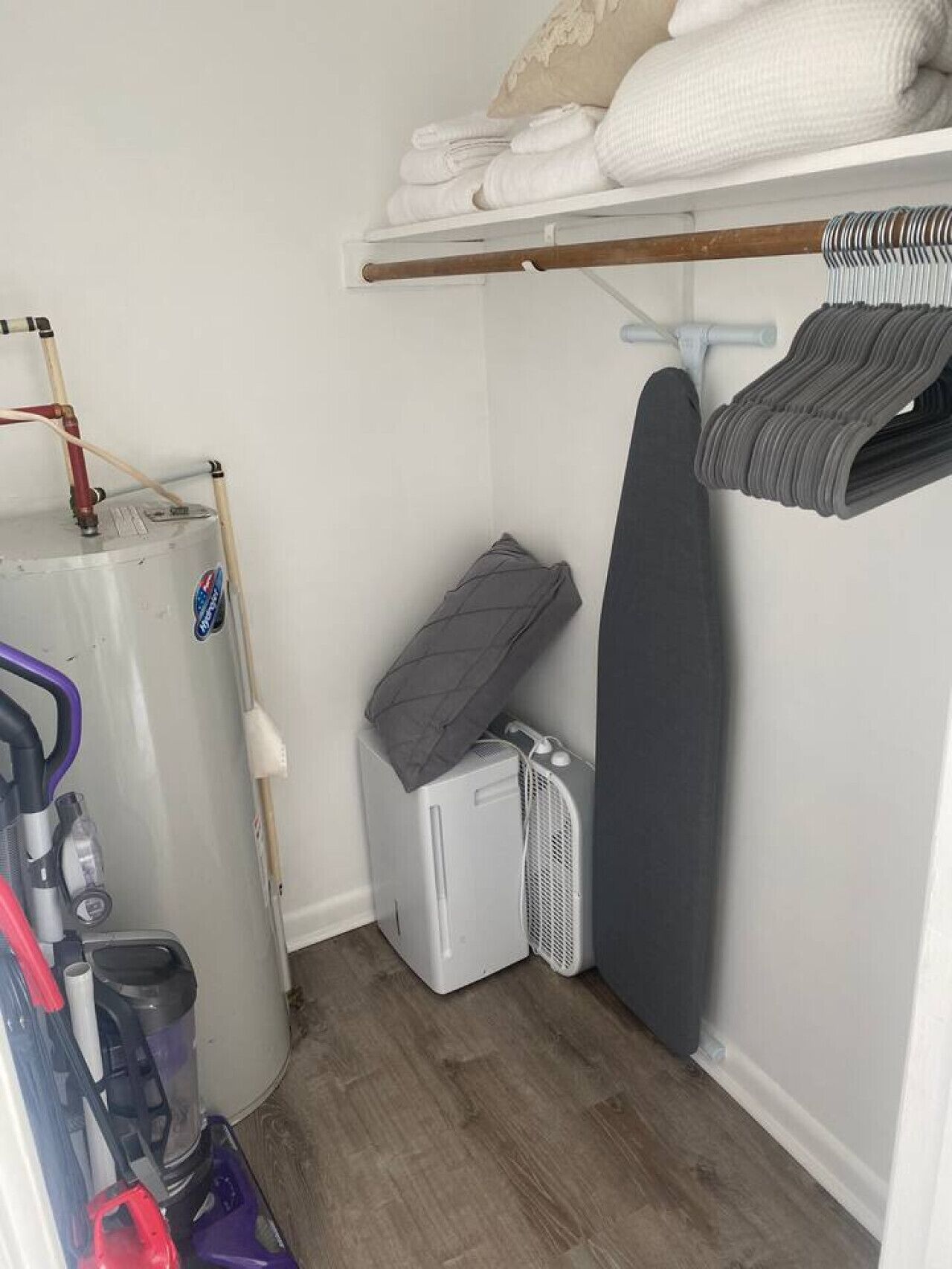 Une petite pièce équipée d’un chauffe-eau, d’un radiateur, d’un petit espace de rangement et d’une étagère où sont pliées des serviettes.