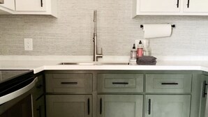 A kitchen with a sink, a faucet, and a countertop with a roll of paper towels and a bottle of soap. - Cocína Vèrde of #swansboro (Swansboro)