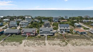 An aerial view of a coastal residential area with houses, a beach, and a view of the ocean. - Oceanfront home with breathtaking views, West! (Emerald Isle)