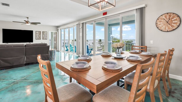 A spacious dining area with a wooden table set for four, surrounded by wooden chairs. - Tranquility Bayview House-Ocean Front with pool, boat basin and boat ramp (Little Torch Key)