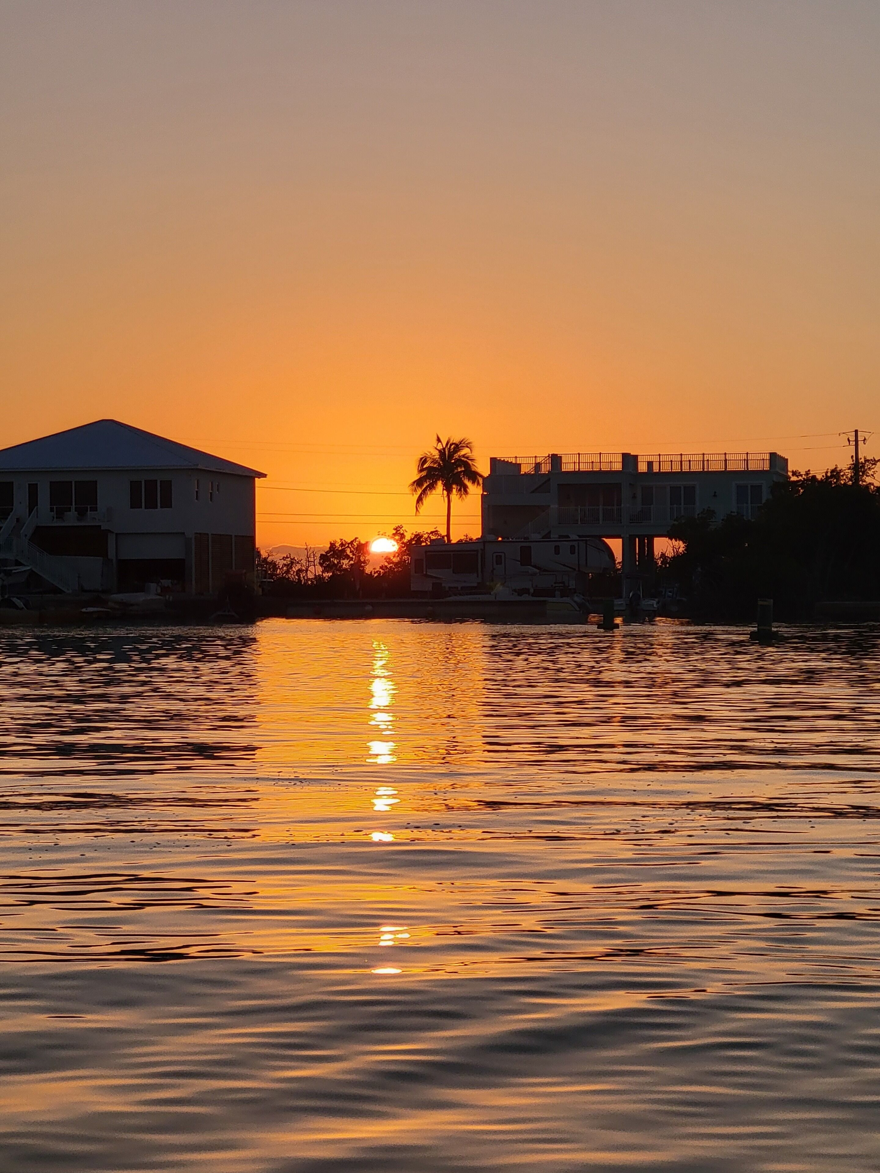 Un atardecer sobre aguas tranquilas con edificios silueteados contra el cielo.