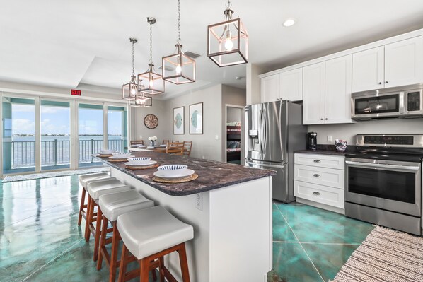 A modern kitchen with a large island, stainless steel appliances, and a view of the ocean. - Tranquility Bayview House-Ocean Front with pool, boat basin and boat ramp (Little Torch Key)