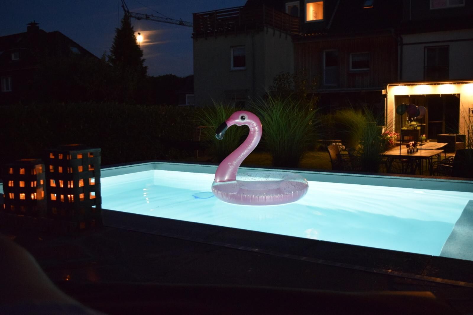 A swimming pool with a pink flamingo float.