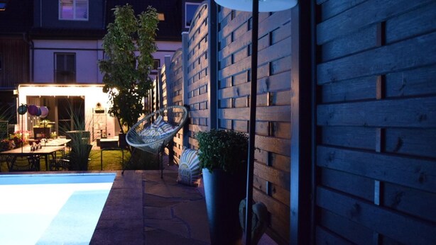 A patio area with a pool, outdoor furniture, and a hanging chair.