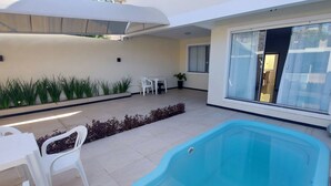 A pool area with a blue pool, white chairs, and a small table. - COPFL0101 - Engenheiro Alves de Souza (Salvador)