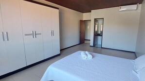 A bedroom with a large bed, a wardrobe, and a mirror. - COPFL0101 - Engenheiro Alves de Souza (Salvador)