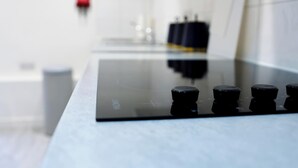 Eine moderne Küche mit einer schwarzen Induktionskochplatte und vier Bedienknöpfen.