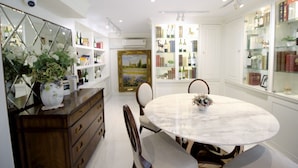A dining area with a marble table, chairs, a vase with flowers, and bookshelves filled with books and wine bottles. - Sasha House-Hotel-Senanikom (Bangkok)