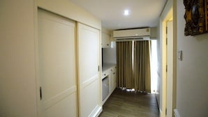 A narrow hallway with a wooden floor, a white door on the left, and a beige wall with a decorative mirror on the right. - Sasha House-Hotel-Senanikom (Bangkok)