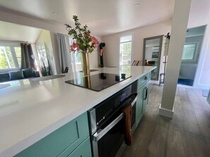 Una cocina moderna con una isla central, electrodomésticos integrados y vistas al exterior.