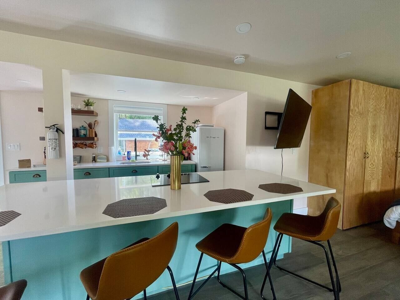 Una cocina moderna con una isla central, taburetes de bar y un mueble grande de madera.