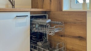 Una cocina moderna con lavavajillas, armarios de madera y ventana con vistas al exterior.