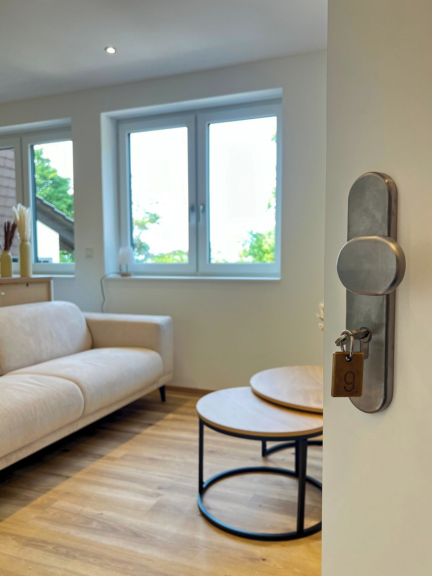 Un salón moderno con un sofá blanco, una mesa redonda de madera y una cerradura de puerta instalada en la pared.