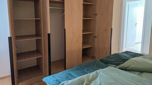 Un dormitorio con cama, un armario de madera y una puerta que da a un balcón.