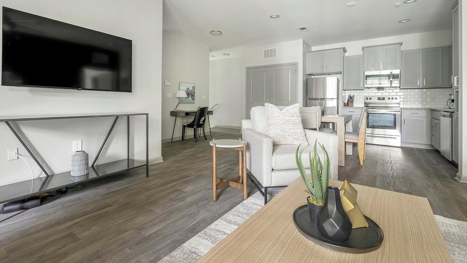 A modern apartment with a living room, dining area, and kitchen.