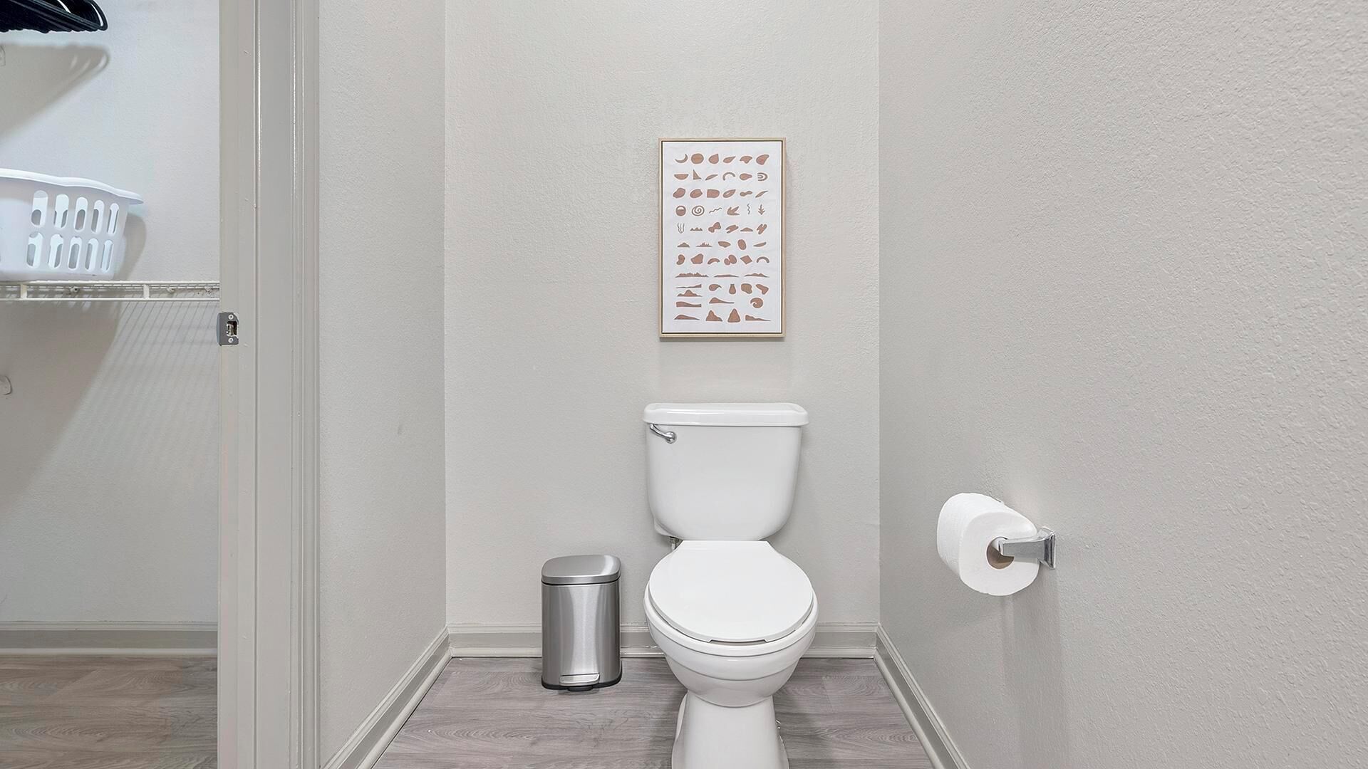 Une salle de bain équipée de toilettes, d’une poubelle et d’un porte-rouleau de papier toilette.
