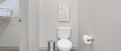 Une salle de bain équipée de toilettes, d’une poubelle et d’un porte-rouleau de papier toilette.