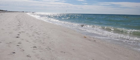 A beach with footprints and waves.