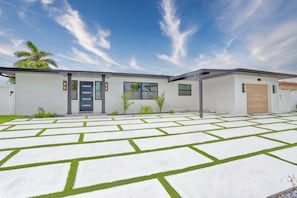 A modern two-story house with a flat roof, a front door, and a garage.