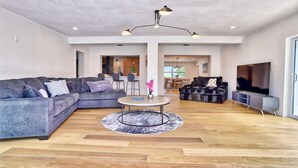 A spacious living room with a sectional sofa, a round coffee table, and a TV. - Parrots Cove (St. Pete Beach)