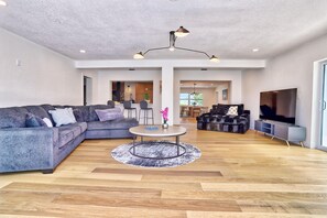 A spacious living room with a sectional sofa, a round coffee table, and a TV.