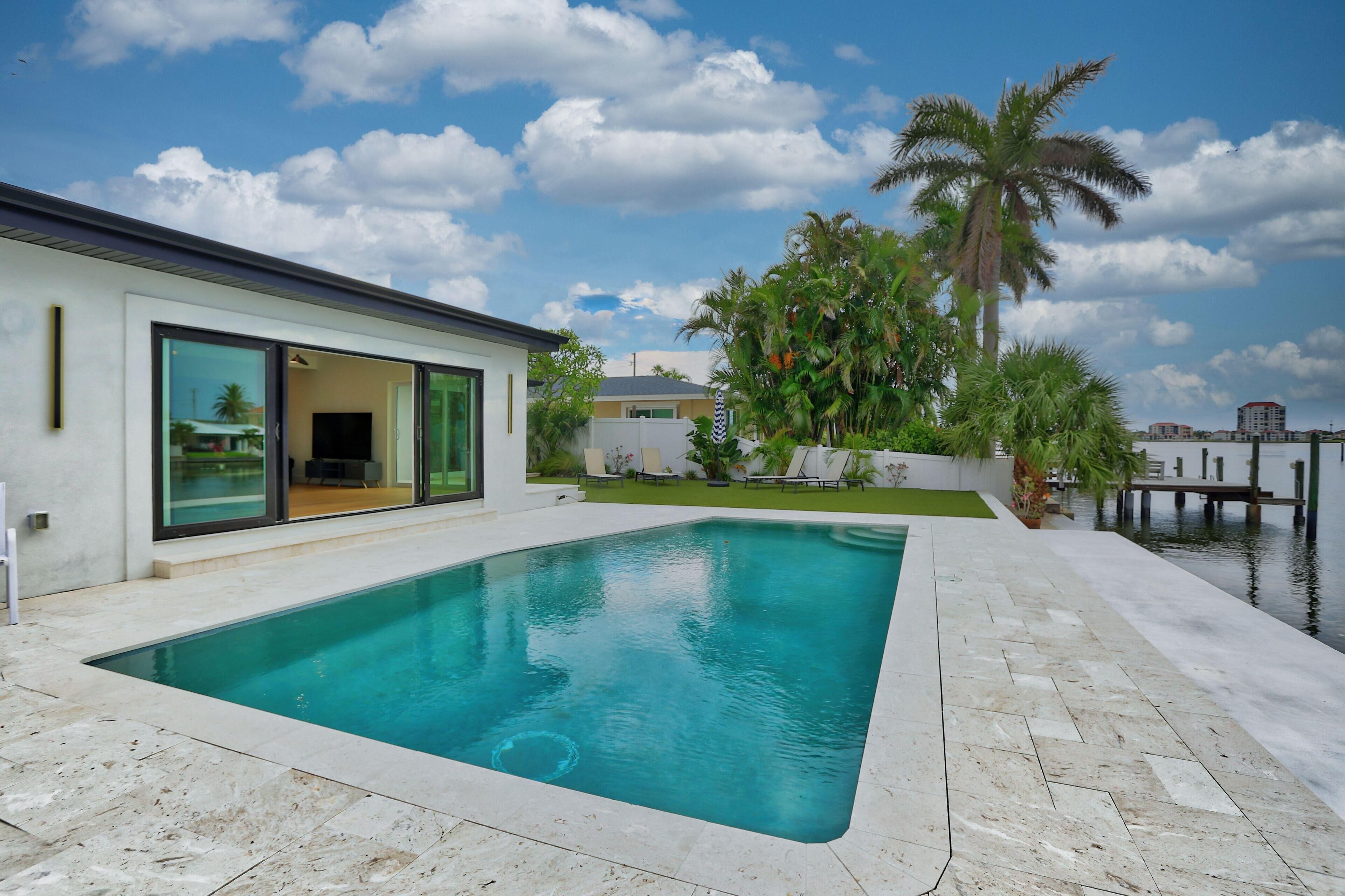 Une maison moderne dotée d’une piscine, de grandes portes-fenêtres coulissantes et offrant une vue sur l’eau.