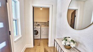 A hallway leading to a laundry area with a wooden floor and a mirror on the wall. - Parrots Cove (St. Pete Beach)