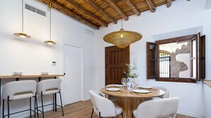 Un comedor con una mesa redonda de madera, cuatro sillas e iluminación colgante.