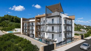 Un immeuble résidentiel à plusieurs étages, doté de balcons, d’une piscine et d’une voiture garée devant.