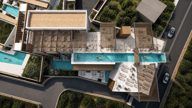 Vue aérienne d’un hôtel moderne doté d’une piscine sur le toit, de plusieurs espaces de détente et d’un grand bâtiment à toit plat.