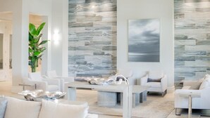A modern living room with a large stone wall, white furniture, and a large window.