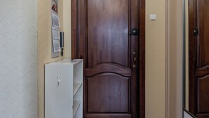 A hallway with a wooden door, a white cabinet, and a hanging light fixture. - Family apartments near Gorky Park (Minsk)