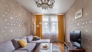 A living room with a sofa, a coffee table, a TV, and a patterned wall. - Family apartments near Gorky Park (Minsk)