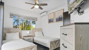 A hotel room with two beds, a ceiling fan, a TV, and a wardrobe. - Private Pool! 3-Min To The Beach (Noord)