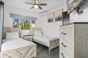 Ett hotellrum med två sängar, en takfläkt, en TV och en garderob.