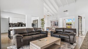 A spacious living area with two leather sofas, a wooden coffee table, and a large window. - Private Pool! 3-Min To The Beach (Noord)