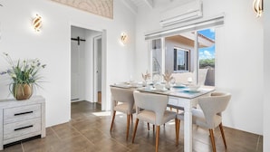 A dining area with a table set for four, a potted plant, and a ceiling fan. - Private Pool! 3-Min To The Beach (Noord)