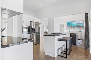 A modern kitchen with a central island, stainless steel appliances, and a bar area.