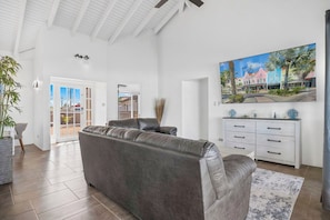 A spacious living room with a leather sofa, a white cabinet, and a large painting of colorful buildings.