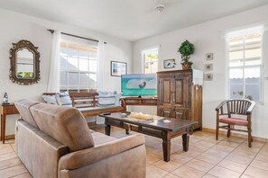 Un salon comprenant un canapé, une table basse, un téléviseur et un meuble en bois.