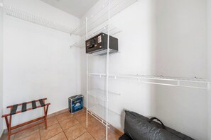 Une pièce avec des étagères blanches, un petit banc en bois et un sac noir.