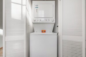 Een kleine, witte wasruimte met een voorlader wasmachine en een droger.