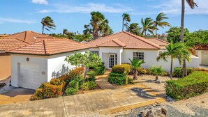 A residential property with a red-tiled roof, white walls, and a well-maintained garden with various plants and a palm tree. - Tierra del Sol home w/ private pool and BBQ! (Noord)
