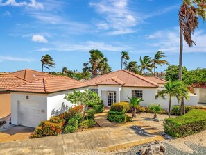 A residential property with a red-tiled roof, white walls, and a well-maintained garden with various plants and a palm tree. - Tierra del Sol home w/ private pool and BBQ! (Noord)