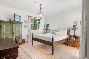 A bedroom with a wooden bed, a desk, a cabinet, and a window with curtains.