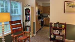 Un salon chaleureux avec un fauteuil à bascule, une bibliothèque et une petite table agrémentée d’objets décoratifs.