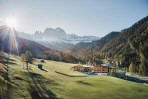 A mountain lodge with multiple buildings, a fenced property, and a clear view of the surrounding mountains. - Cyprianerhof Dolomit Resort (Tires (BZ))