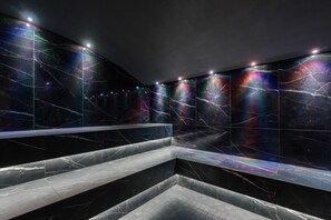 Un baño moderno con paredes de mármol oscuro y una zona de estar central.
