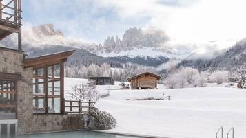 A snow-covered landscape with a wooden cabin and a stone building with large windows.