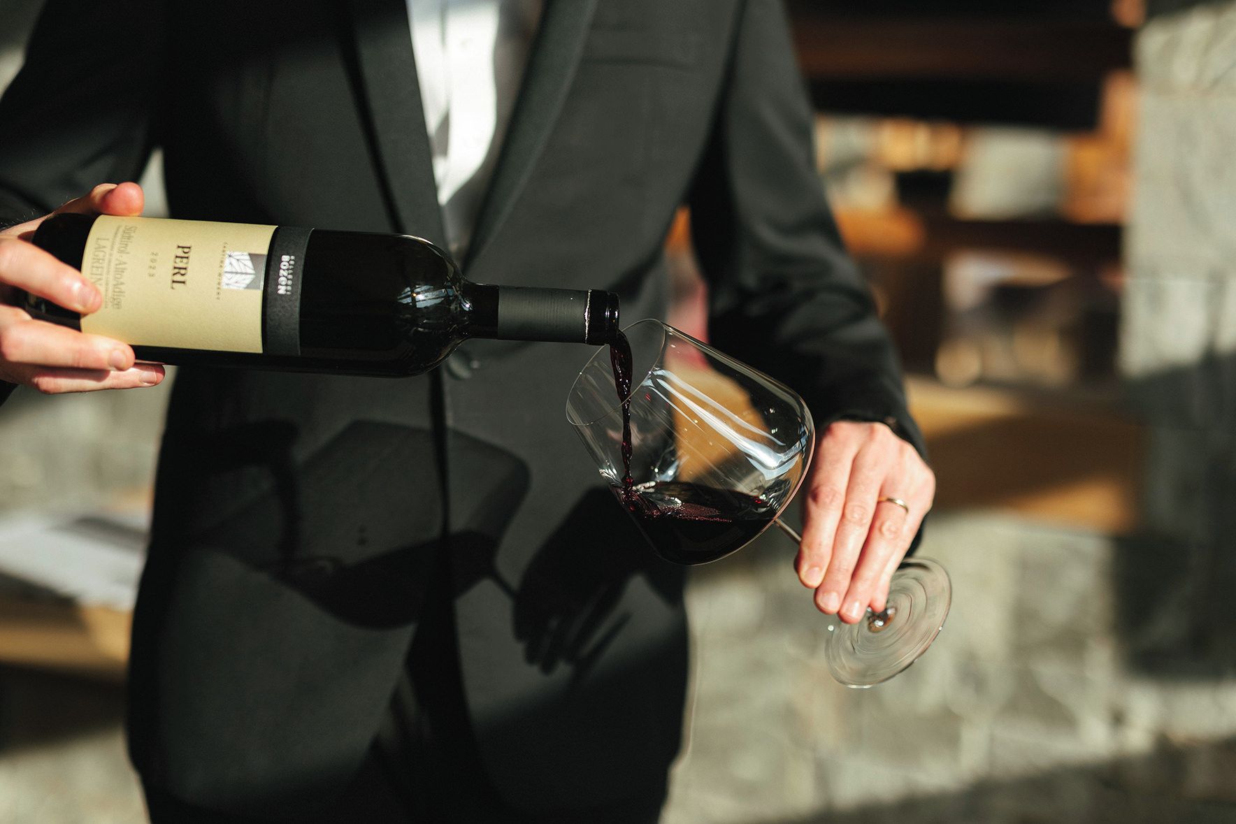 Una persona versa vino da una bottiglia in un bicchiere.